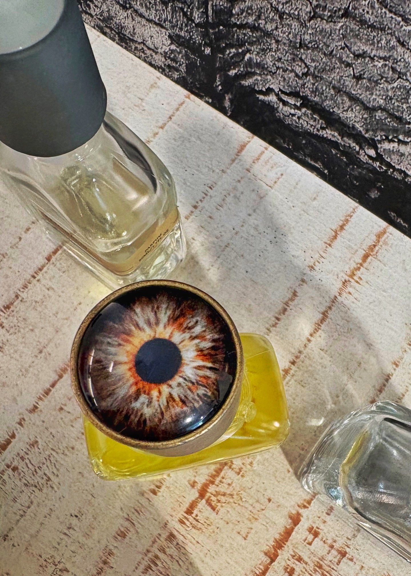 A glass bottle the colour of pressed citrus, and an eye staring back at you from