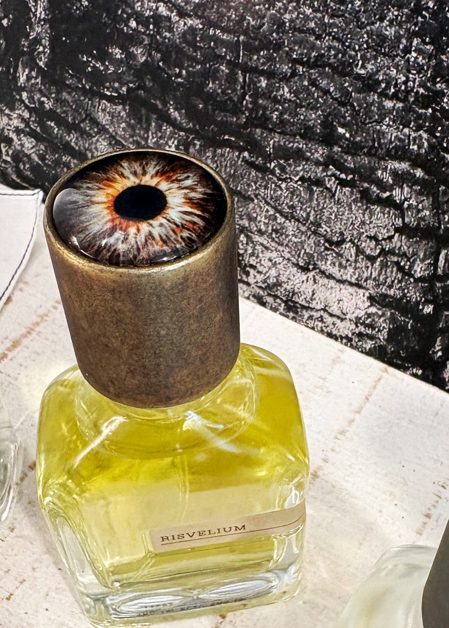 A glass bottle the colour of pressed citrus, and an eye staring back at you from