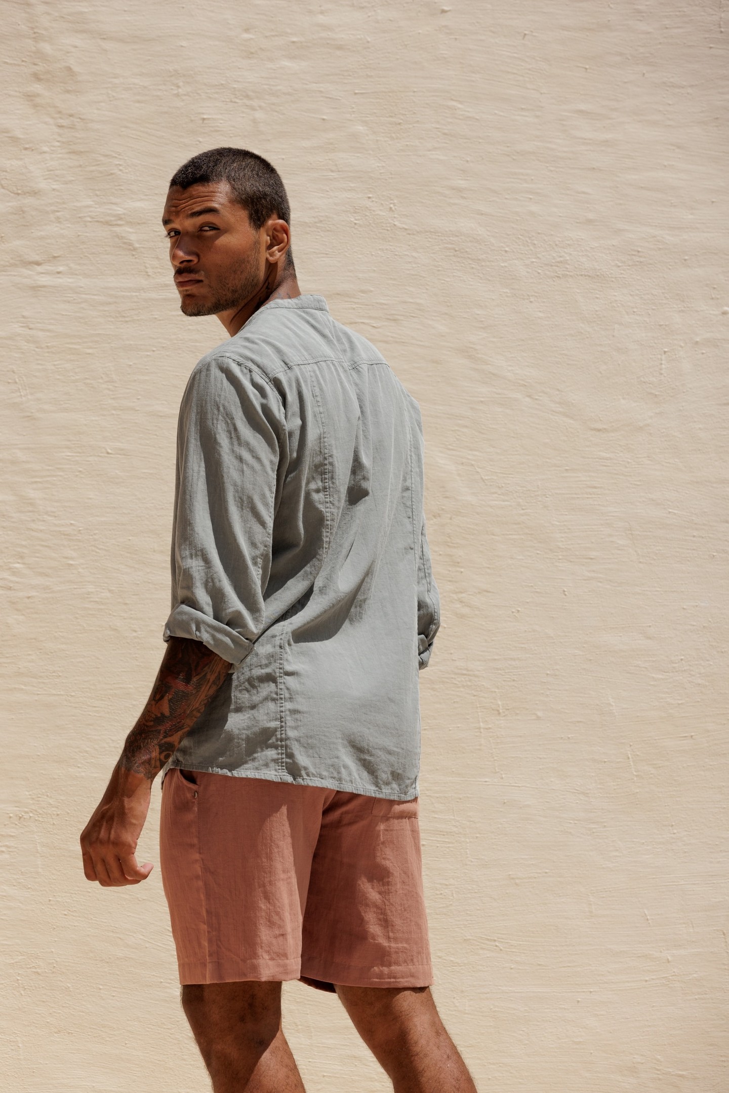 Sage linen against a whitewashed wall, and a terracotta short that looks like it